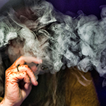 "obscured shot of a women smoking using a vape pen"