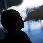 silhouette of a man puffing on an electronic cigarette"