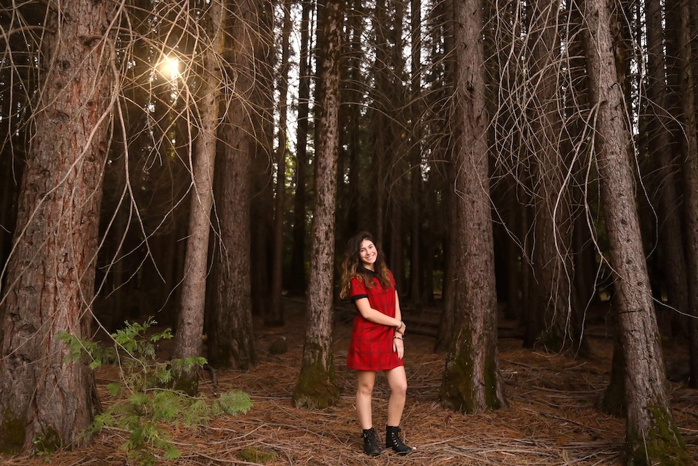Person posing among trees