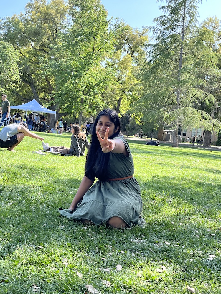 Ashwini posing for for a photo, sitting on the quad
