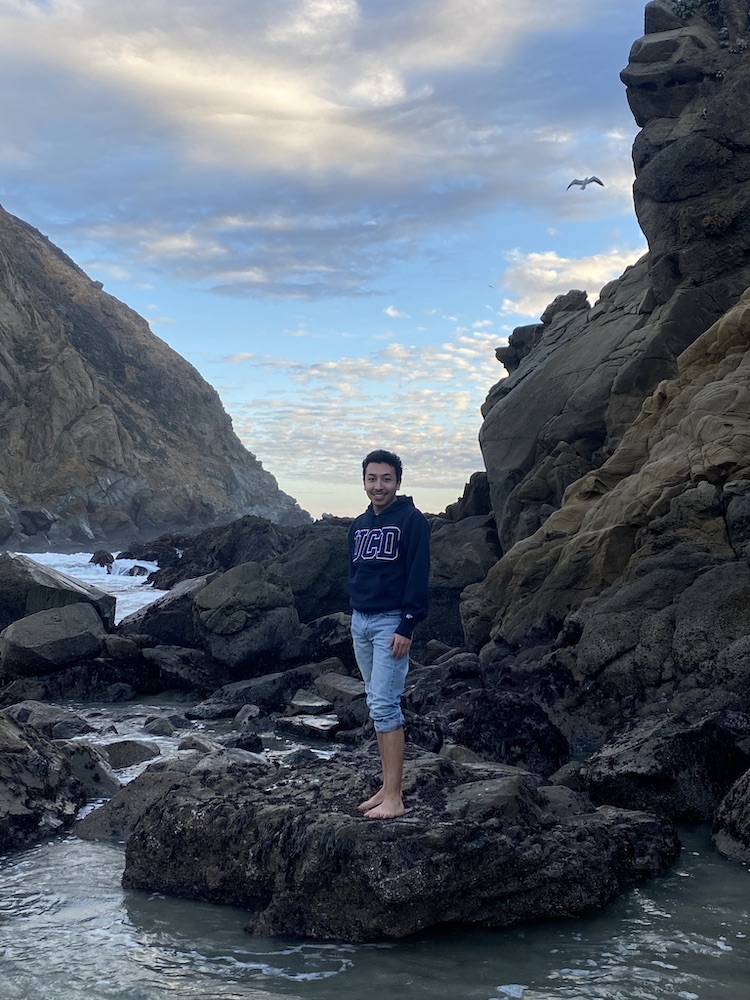Christian standing on a rock near coastal cliffs at the ocean