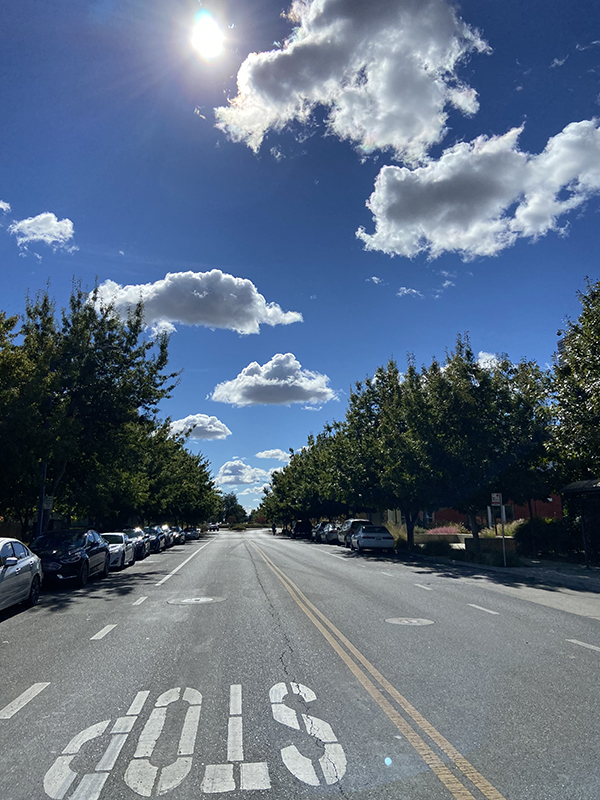 A bright sky with fluffy clouds over an empty street