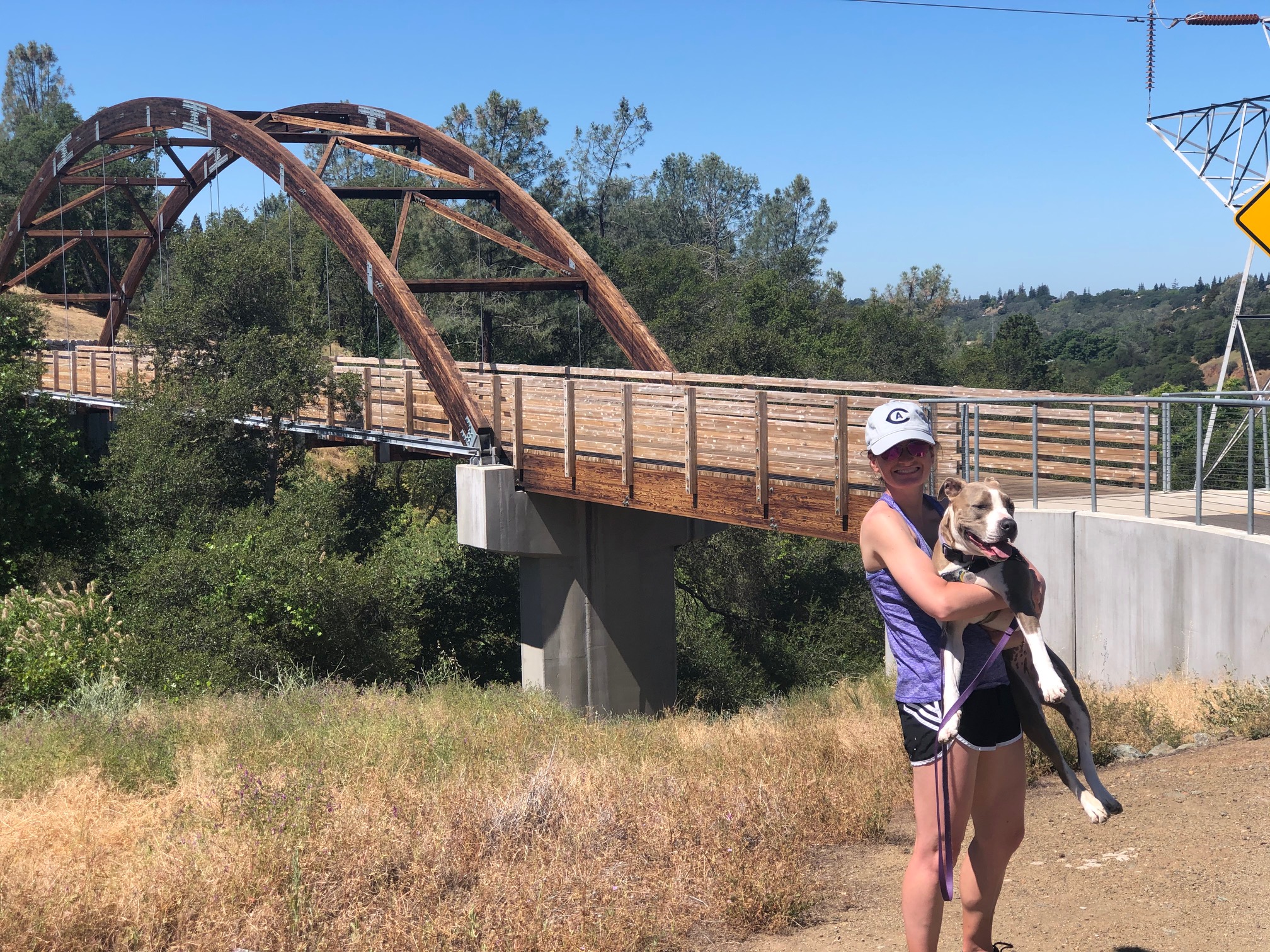 Becky Cuneo in front of a bridge, carrying a dog
