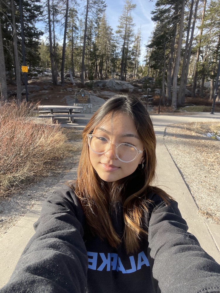 Jade poses for a selfie on a walking trail surrounded by trees