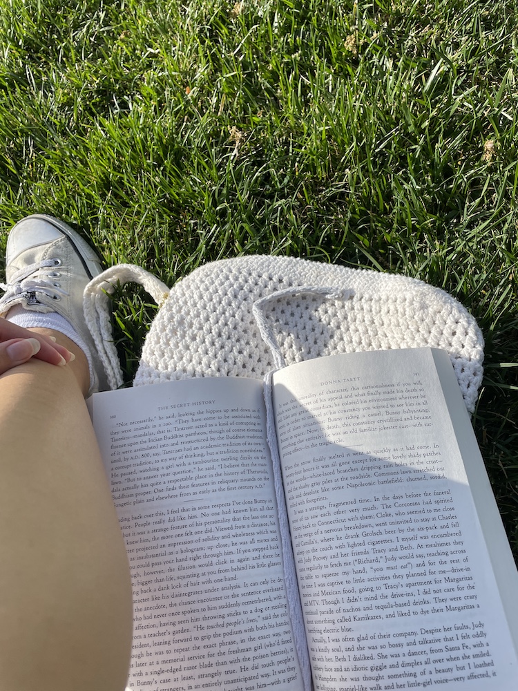Person reading "The Secret History" in the grass