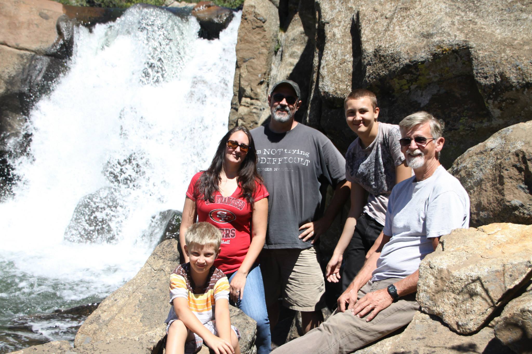 Group of people of different ages posing in front of a waterfall