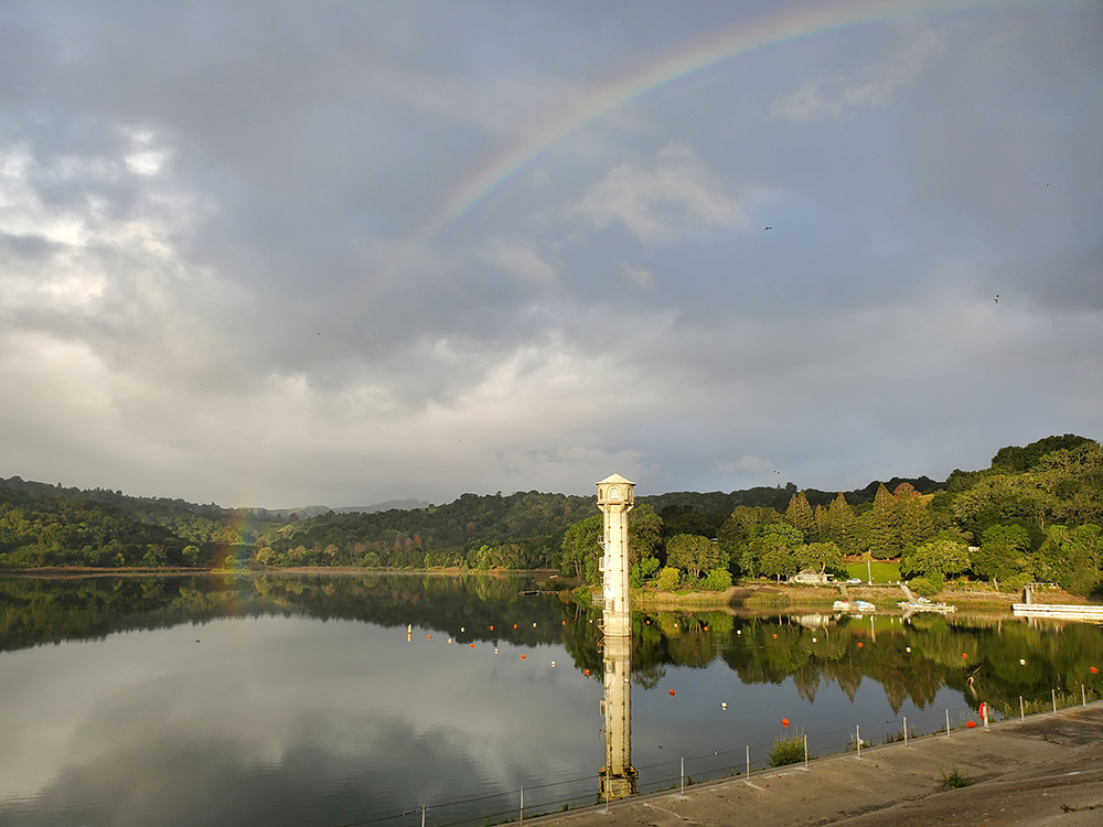 Rainbow over a reservoir surrounded by green hills