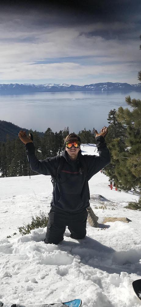 Tyler posing on a snowy peak, with Lake Tahoe in the background
