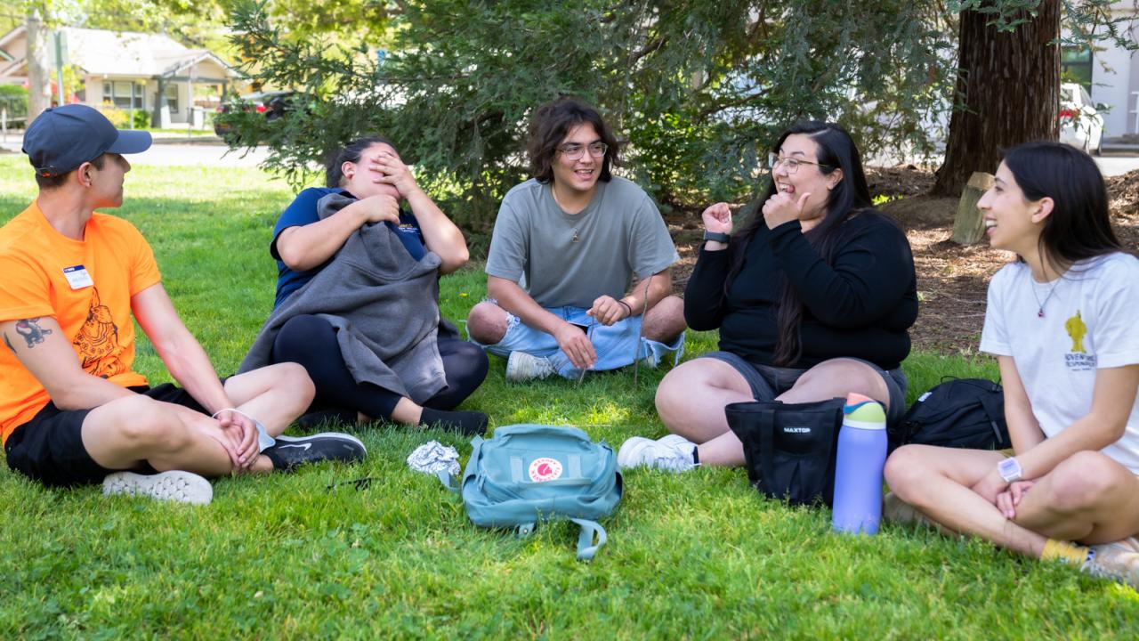 a group of five students enjoying each other's company and laughing while sitting together on the Quad