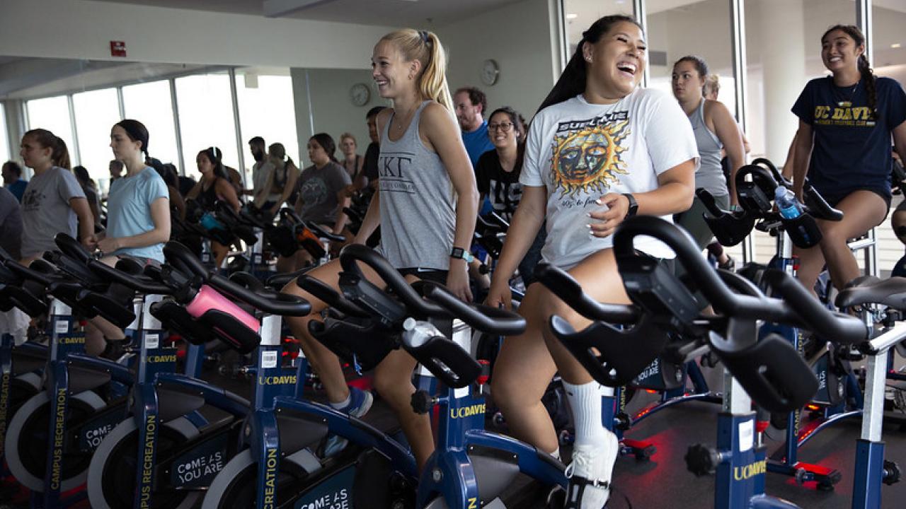 students smiling and laughing while participating in a indoor cycling or spin class