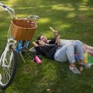 two girls laying on the grass with a bike