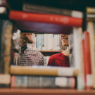 two people viewed with a stack of books