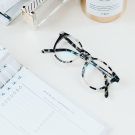 pair of glasses and diary sitting on a desk