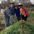 four individuals pose for a photo with a green mulch pile