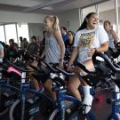 students smiling and laughing while participating in a indoor cycling or spin class