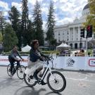 two women biking in front of the CA State Capitol during SABA's costume ride