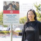 Dr. Tong holding a smoke-free campus sign
